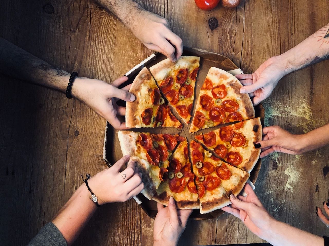 galera pegando uma fatia de pizza